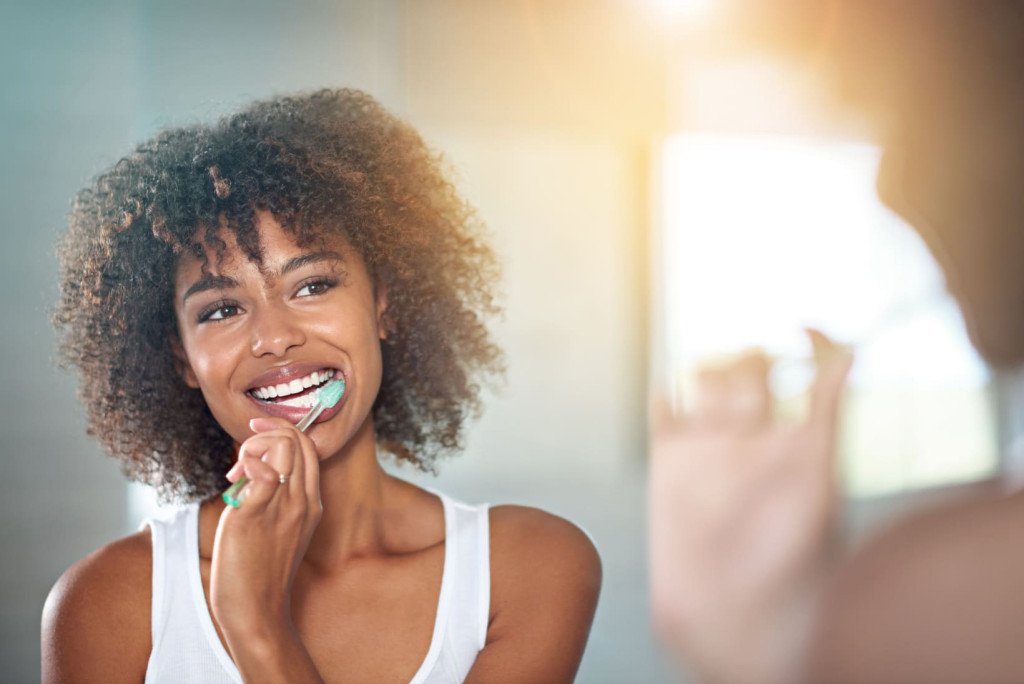 brossage des dents d'une jeune femme se brossant les dents dans la salle de bains.