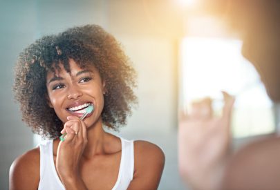 brossage des dents d'une jeune femme se brossant les dents dans la salle de bains.