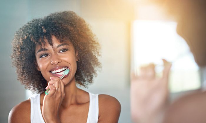 brossage des dents d'une jeune femme se brossant les dents dans la salle de bains.