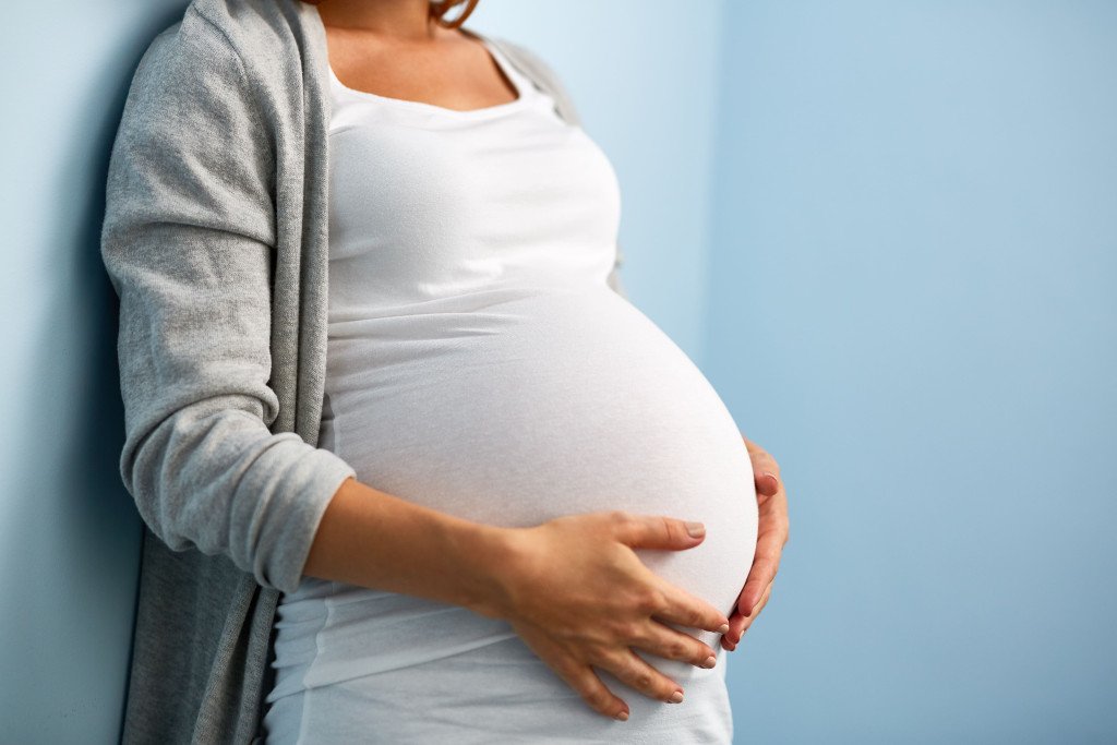 Femme enceinte tenant doucement son ventre rond, symbolisant la maternité et l'attente d'un enfant.