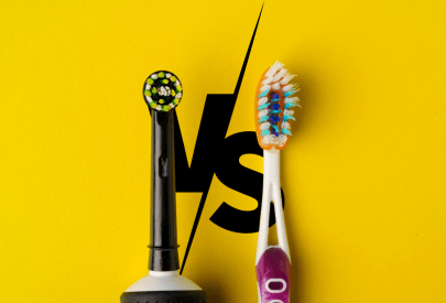 Comparaison entre une brosse à dents électrique et une brosse à dents manuelle sur fond jaune avec un 'VS' en arrière-plan.