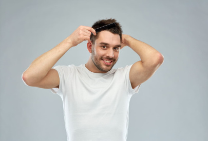 Un homme souriant se peigne les cheveux, illustrant la réussite des étapes de la greffe de cheveux.