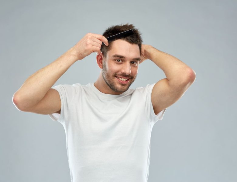 Un homme souriant se peigne les cheveux, illustrant la réussite des étapes de la greffe de cheveux.