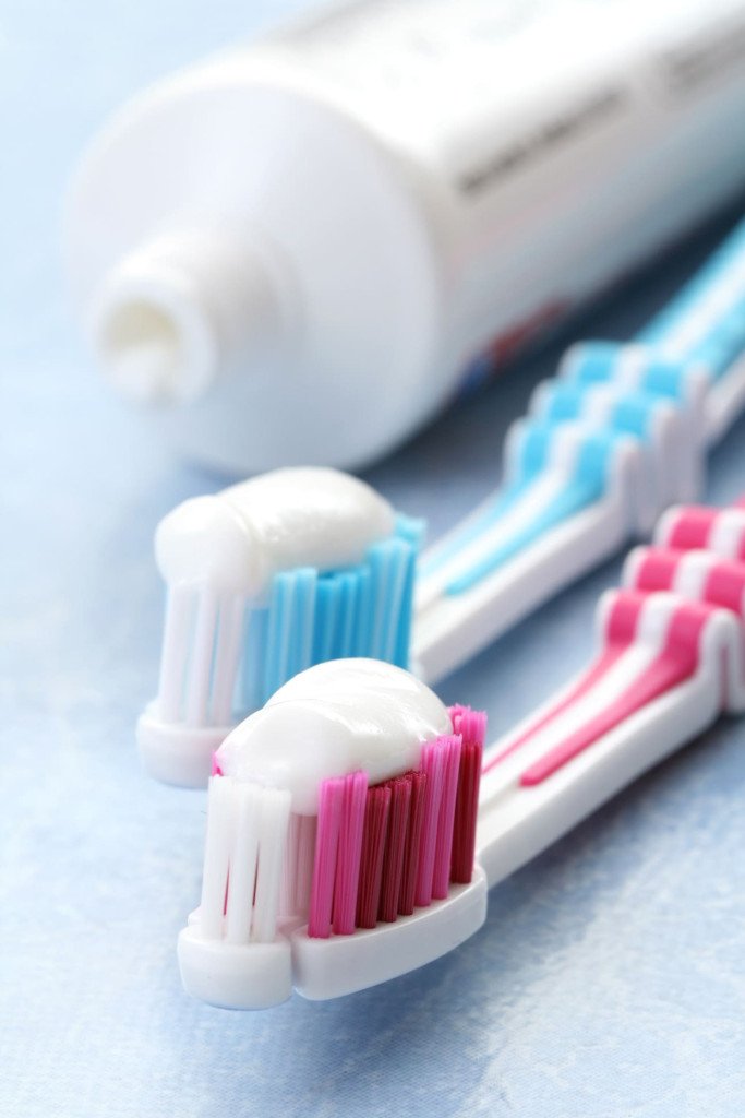 Brosses à dents avec du dentifrice, illustrant l'importance du fluor pour la santé dentaire.