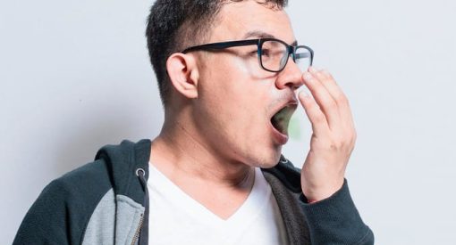 Un homme se couvre la bouche avec la main, illustrant le problème de la mauvaise haleine.