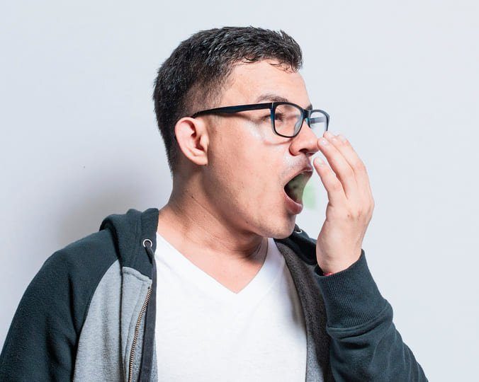Un homme se couvre la bouche avec la main, illustrant le problème de la mauvaise haleine.