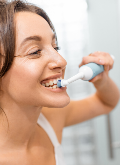 femme qui se brosse les dents avec une brosse à dents électrique