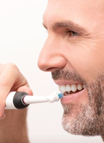 homme se brossant les dents et utilisant du fil dentaire pour sa prothèse dentaire