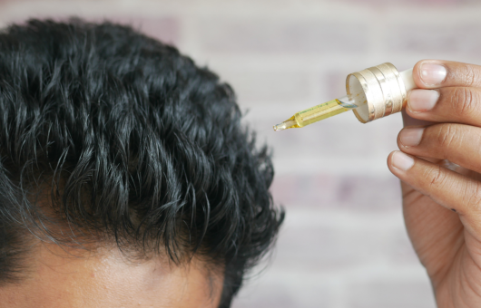 Homme qui utilise de l'huile de romarin cheveux
