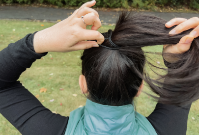 femme qui s'attache les cheveux en queue de cheval