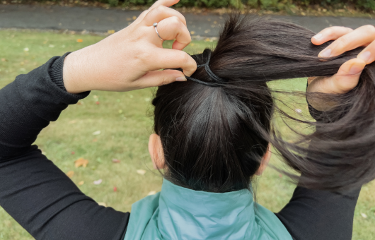 femme qui s'attache les cheveux en queue de cheval